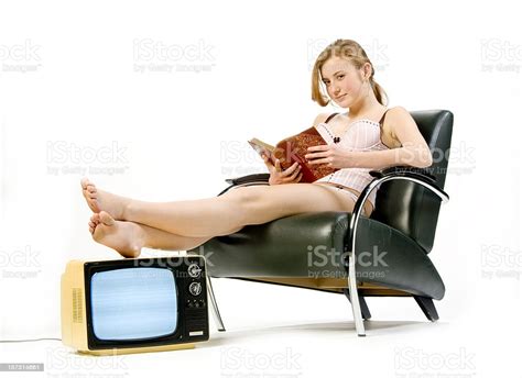 teenage redhead reading book with feet on tv set stock
