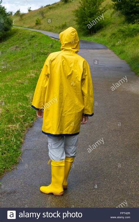 junge frau trägt einen gelben regenmantel und kautschuk stiefel wandern in der natur stockfoto