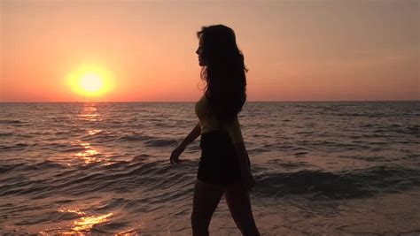 a man carrying a woman in his arms is silhouetted against an ocean sunset stock footage video