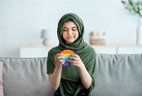 Portrait Of Lovely Indian Teen Girl In Hijab Playing With Bright Pop It