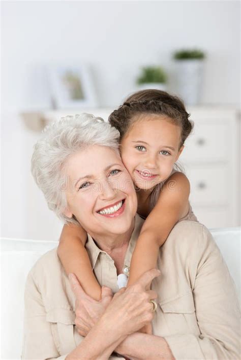 An Older Woman Hugging Her Granddaughter On The Couch Royalty Images