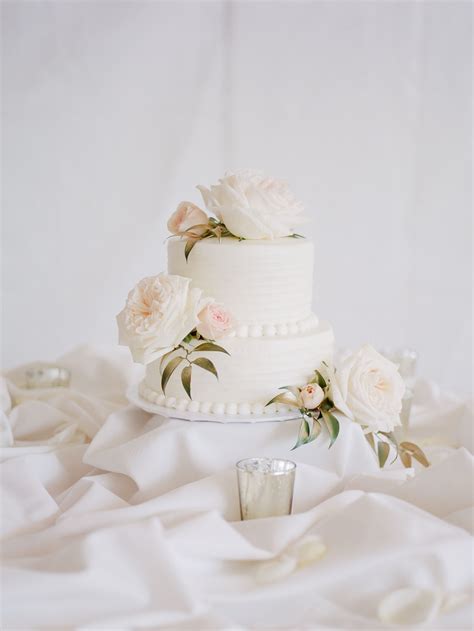 two tier white wedding cake with lush roses