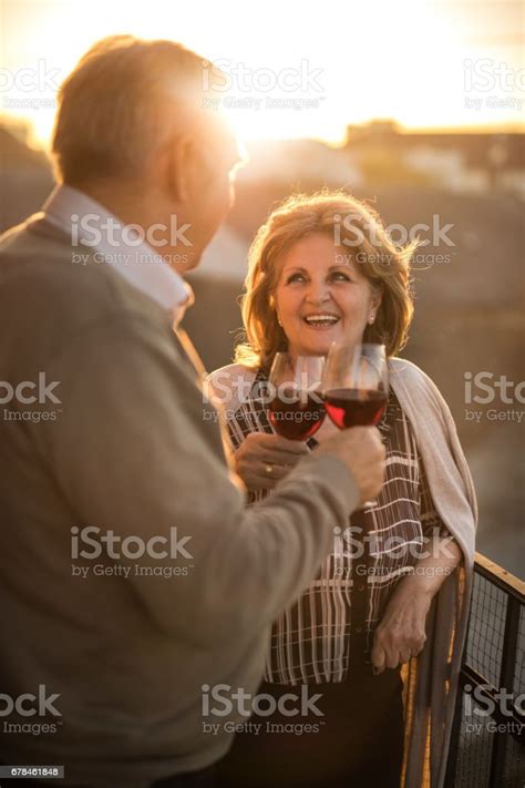 mujer senior feliz brindando con su marido en una terraza al atardecer