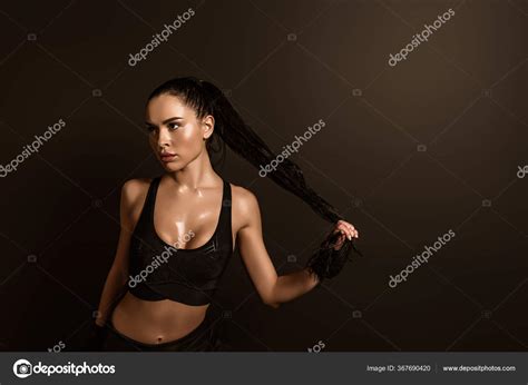 sexy brunetka sportovkyně dotýkající vlasů odvracející izolované Černé