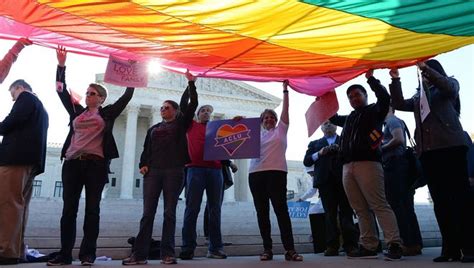 gay marriage advocates hold a rainbow flag in front of the supreme