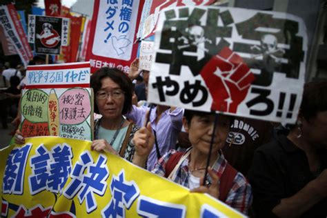 protesters raise placards during a rally against japan s