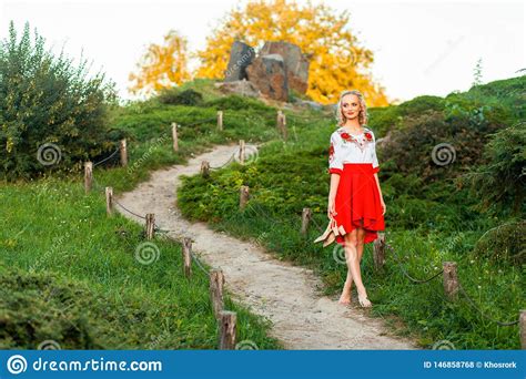 Beautiful Barefoot Woman In Stylish Red White Dress Holding Shoes In