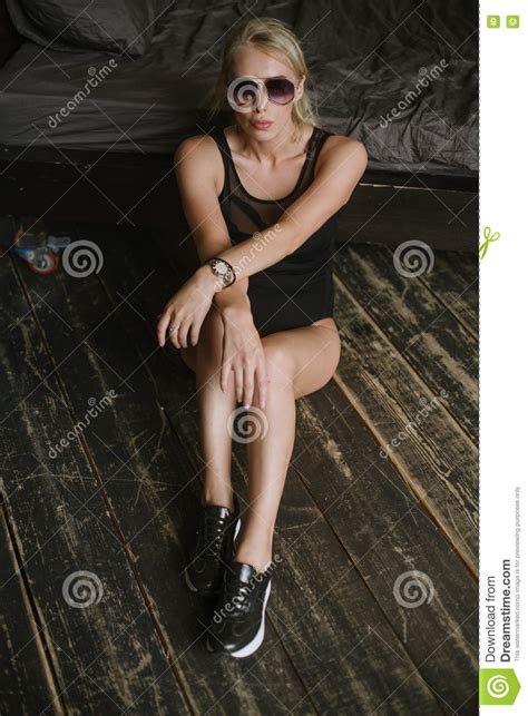 woman posing in sunglasses sitting next to the bed with