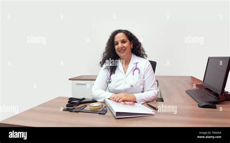 Female Latin Female Doctor Sitting Smiling In Her Office With