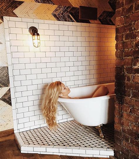 A Woman Sitting In A Bathtub With Long Blonde Hair On The Floor Next To