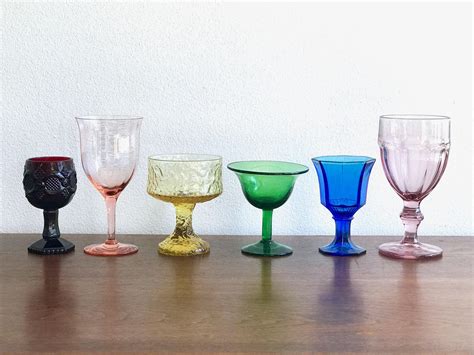 Five Different Colored Wine Glasses Lined Up On A Wooden Countertop
