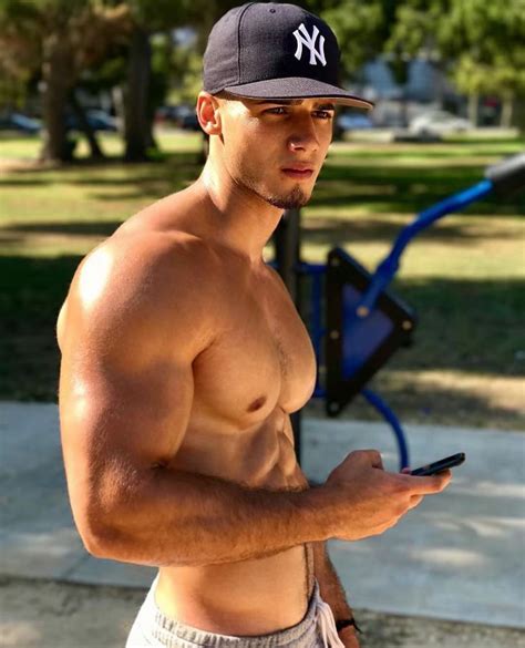 A Man With No Shirt Is Looking At His Cell Phone While Wearing A New