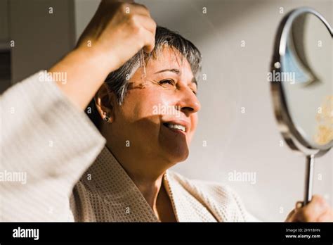 Positive Elderly Woman Using Moisturizing Serum While Having Skincare