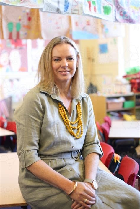 image of female school teacher sitting on a classroom desk austockphoto