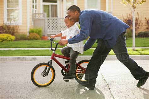 father teaching son  ride bicycle stock photo dissolve