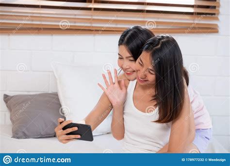 asian lesbian couple using mobile video conferencewith