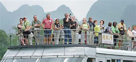 foreign tourists appreciate the lijiang river views on a sightseeing boat