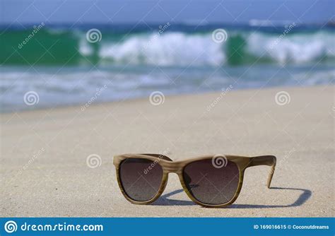 sunglasses on the beach with blurry splashing waves in background stock