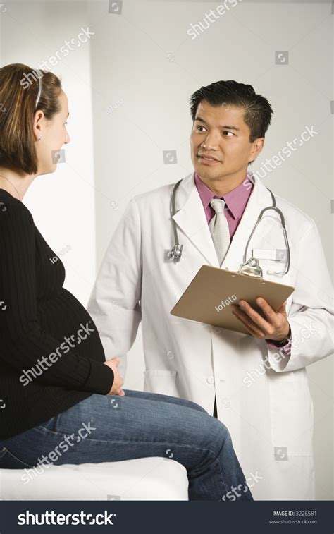 Asian American Male Doctor Examining Caucasian Pregnant Female Patient