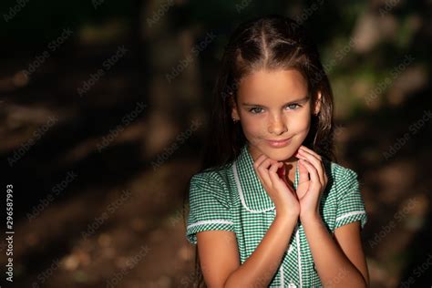 pretty little brunette girl posing in forest near tree with sun light