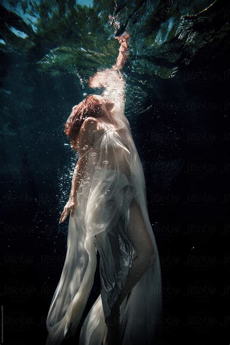 woman underwater reaching to the surface stocksy united