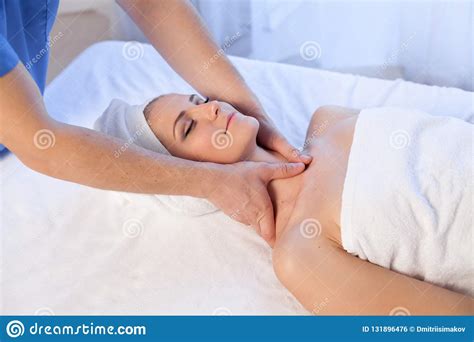 a massage therapist makes a woman face and neck massage in the spa