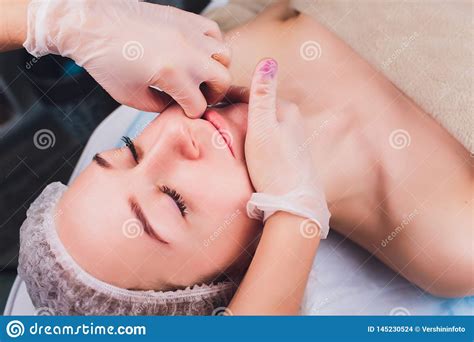 cosmetologist makes a buccal massage of the patient`s facial muscles