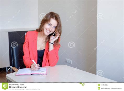 Secretary Talking On Mobile Phone And Writing Notes While
