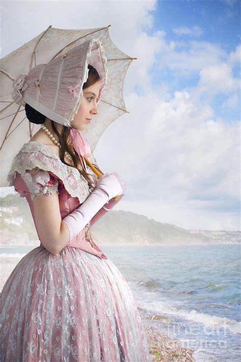 victorian woman with bonnet and parasol on the beach looking out
