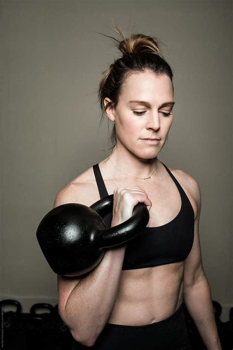 woman working out in the home gym with kettle bell by stocksy