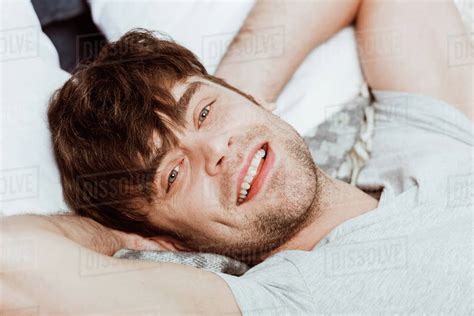 Close Up Portrait Of Young Man Looking At Camera And Laying In Bed