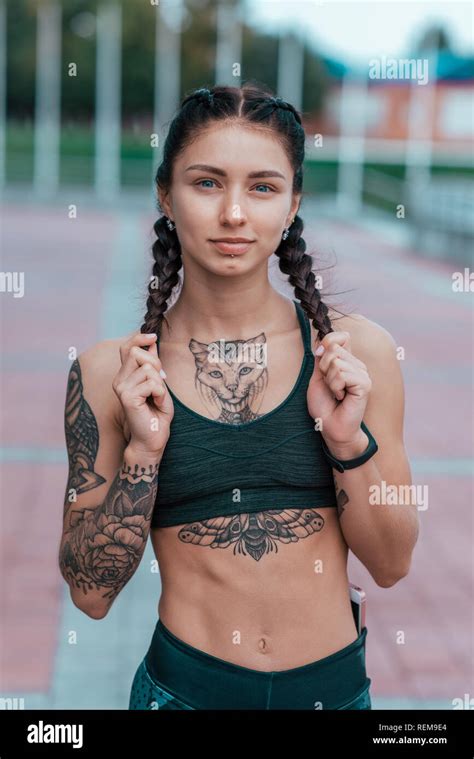 a beautiful girl is an athlete with tanned skin and cat tattoos happy