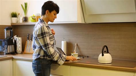 Woman Standing In The Kitchen And Pouring Boiling Water To The Cup