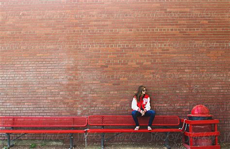 teen girl sits on back of metal bench looking away stocksy united