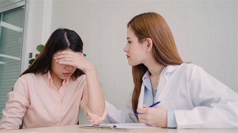 Doctor Talking To Unhappy Teenage Patient In Exam Room Asian Wo