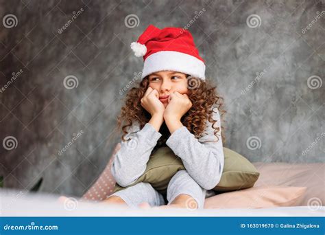 Curly Haired Beautiful Uhappy Tween Girl In Santa Hat And Pajamas