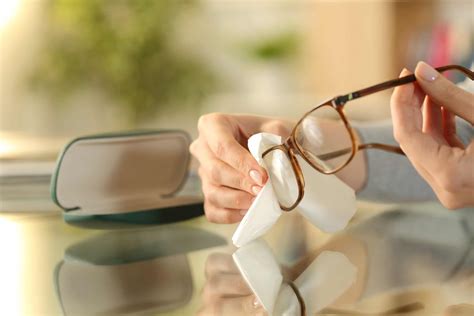 woman hands cleaning glasses with tissue at home sight eye clinic