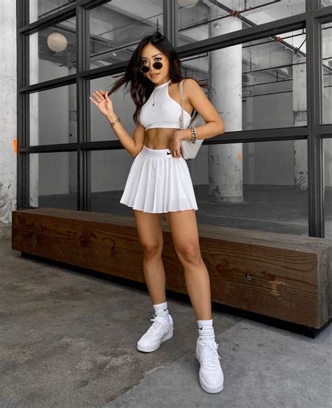 A Woman Posing In A White Outfit And Tennis Shoes With Her Hands On Her