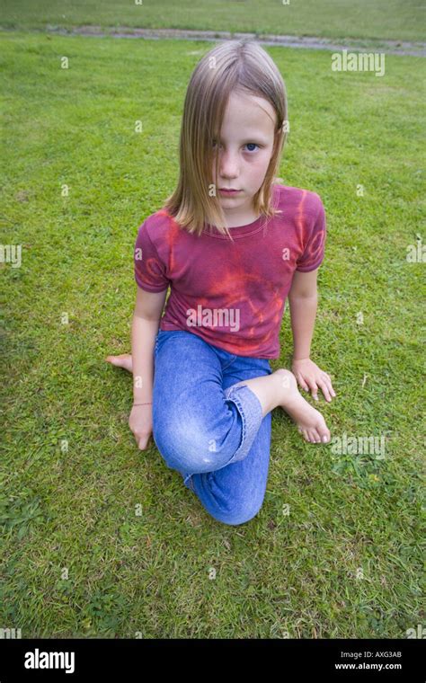 uk cornwall  year  girl sitting cross legged  grass lawn park