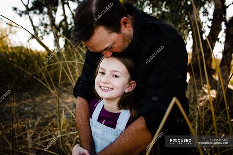 dad kissing daughter on top of head at park in chula vista — hug