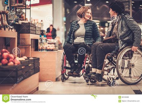 twee glimlachende gehandicapte vrouwen  rolstoel  een warenhuis stock afbeelding image