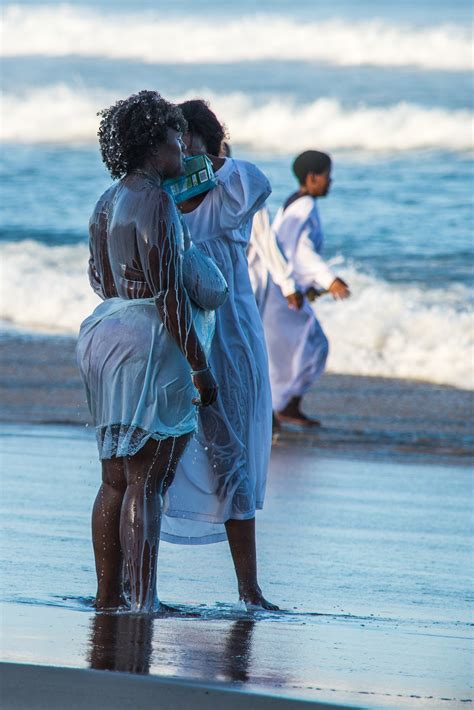 woman bathing another woman in milk on the shore of the indian ocean