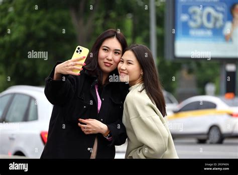 asian girls taking selfie on smartphone camera while walking on city