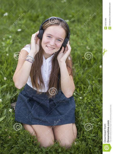 cute teen girl in headphones enjoys the music on the green
