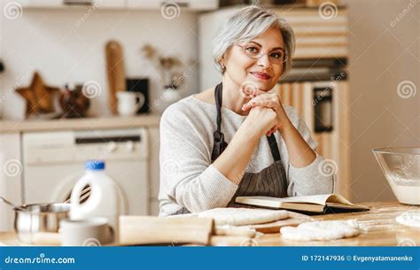 Happy Old Woman Granny Cooks In Kitchen Kneads Dough Bakes Cookies