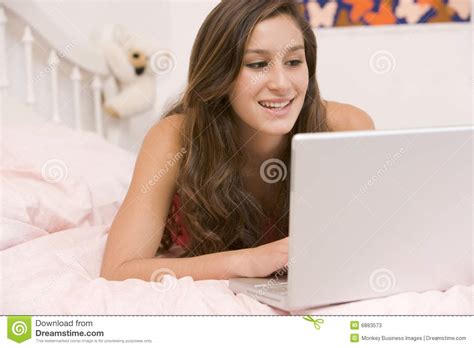 teenage girl lying on her bed using laptop stock image