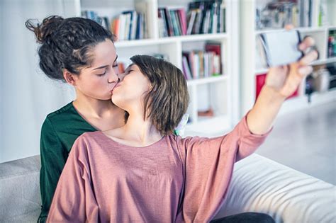 lesbijska para całuje się podczas robienia selfie w domu zdjęcia