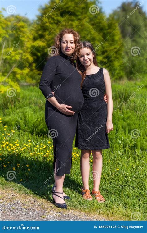 Portrait Of Pregnant Mother With Daughter In Black Dress In Green Park