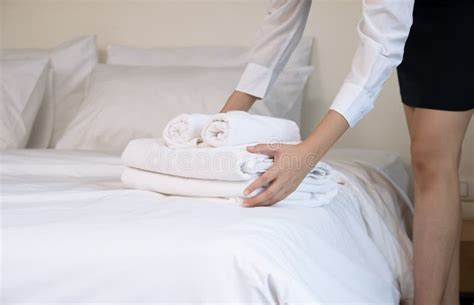 Room Service Maid Putting Stack Of White Towels On Bed In Hotel Room