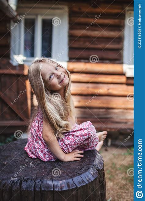 blonde girl with long hair sitting on wood stub on backyard of old